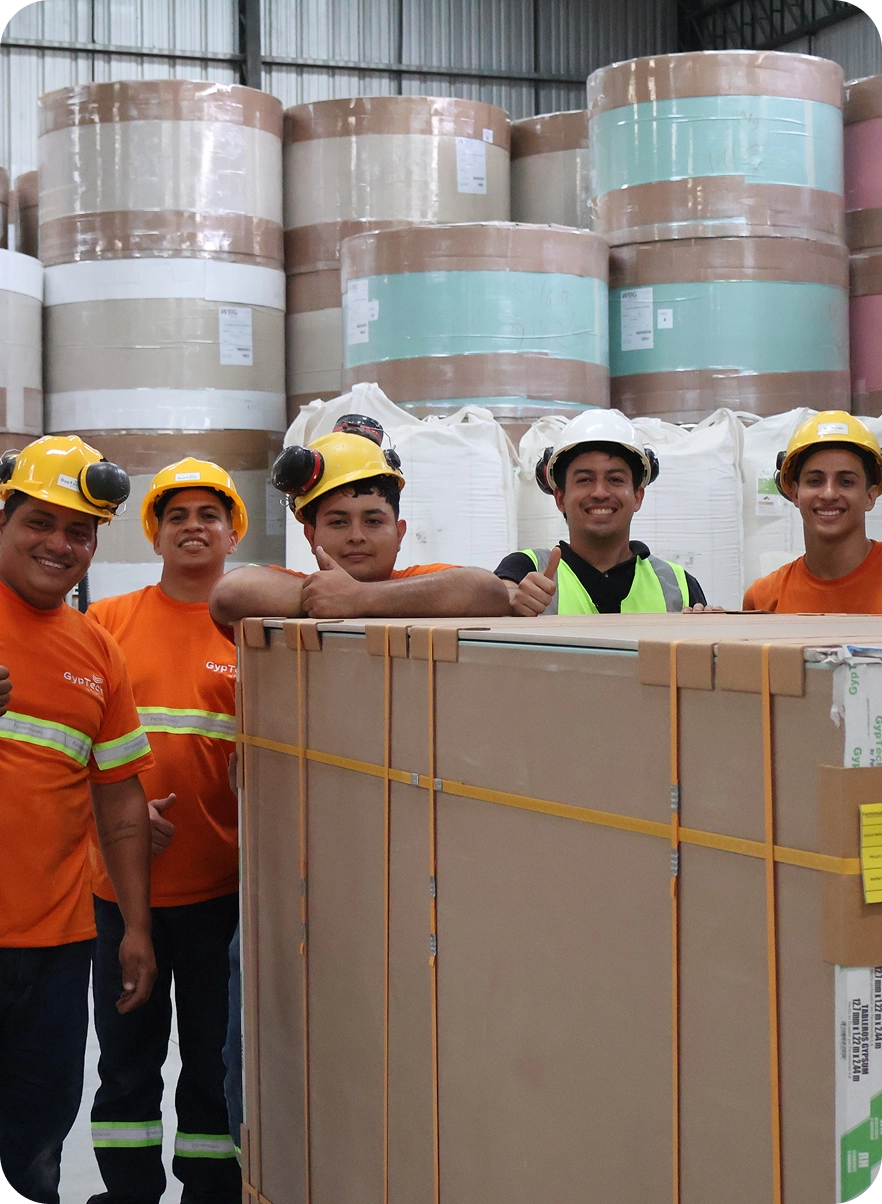 Equipo de producción en planta de Gyptech junto a carga de paneles de yeso listos para distribución
