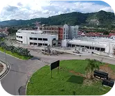 Vista frontal de la Plaza Comercial Galerías en proceso de construcción, rodeada de áreas verdes y montañas