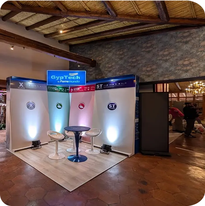 Stand de evento GypTech by Ferremundo con sillas, mesa y paneles iluminados en un evento de exhibición